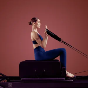 kobieta wykonuje ćwiczenie na reformer, są to zajęcia Nano Pilates wzmacniające mięśnie głębokie